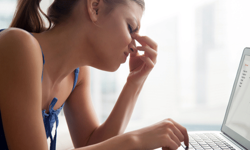 Woman experiencing blurry vision while looking at computer screen